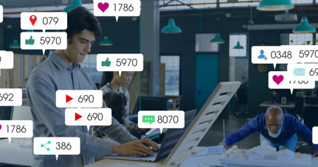 Typing Native American man working at coworking space with scale model and social icons, copy space. Collaboration, innovation, teamwork, modern, professional, creative, digitalの写真素材