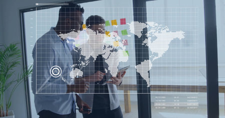 Reviewing data on tablet two analysts wearing casual shirts in office, with plant and map overlay. Collaboration, innovation, modernity, teamwork, technology, professional, productivityの写真素材