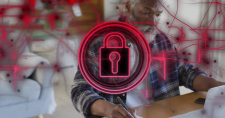 Typing man in plaid shirt working on laptop in living room workspace, with neon padlock overlay....