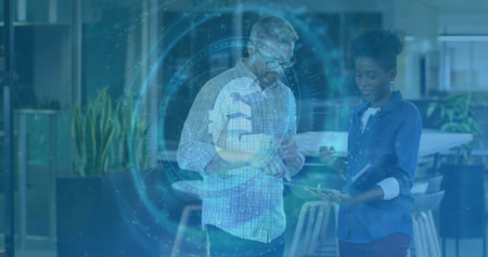 Interacting checked-shirt man and denim-shirt woman using holographic data in office, with tablet....