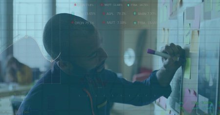 Arranging team lead placing sticky notes on wall board in open office, with laptop, copy space. Collaboration, brainstorming, teamwork, productivity, creative workspace, modern office, organizational toolsの写真素材