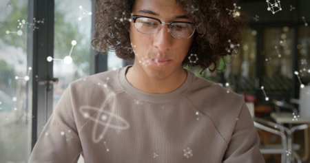 Researcher studying molecular graphics at cafÃ© table near glass door, with glasses and ribbed...