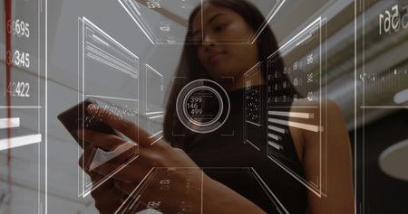 Holding smartphone, woman in black sleeveless top using holographic interface in lobby, data charts....