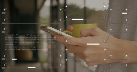 Holding smartphone and yellow mug, gray-shirted man at corridor by mesh fence, overlay, copy space. Technology, modern, industrial, communication, lifestyle, digital, urbanの写真素材