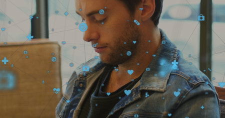 Gazing male wearing denim jacket over dark shirt sitting on seat by window, floating medical icons....