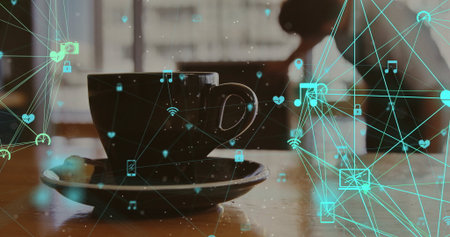 Displaying dark ceramic coffee cup nesting on saucer over table at cafe, with teal network icons....