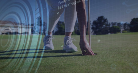 Bending female golfer retrieving golf ball on putting green, with flagstick and digital overlay. Athletic, sportswear, technology, user interface, fitness, outdoor, professionalの写真素材