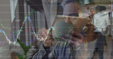 Denim-shirted Asian man sipping coffee from mug in office, with tablet chart overlay. Professional,...