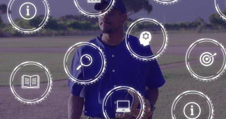 Standing baseball player holding leather glove wearing blue cap on dirt infield, with digital icons. Athlete, sports, stadium, active, outdoors, competition, fitnessの写真素材