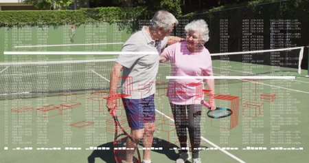 Standing senior couple holding rackets on green tennis court with net, fence and hedge backdrop. Athletics, fitness, recreation, outdoor, vitality, companionship, leisureの写真素材