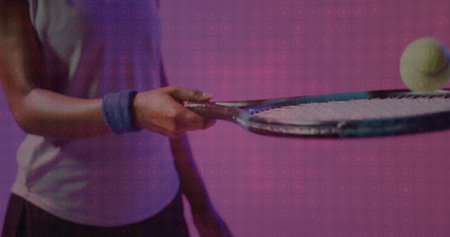 Performing female tennis player with blue wristband balancing yellow ball on racket in studio. Sports, athlete, fitness, concentration, energetic, dynamic, vibrantの写真素材