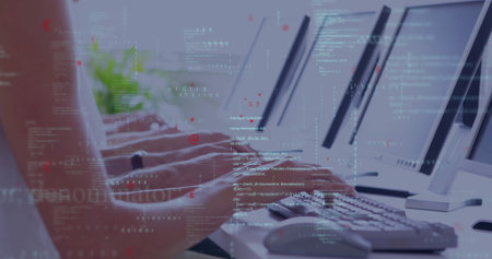 Typing programmer hands pressing keys on keyboards at office row, with monitors, code and plant....