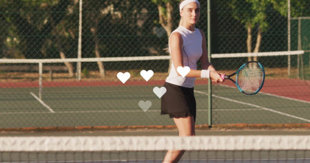 Standing tennis player wearing tennis outfit gripping racket at net on court, with chainlink fence....