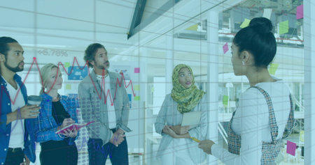 Woman in plaid dress marking glass board in office with sticky notes, graph overlay, copy space....
