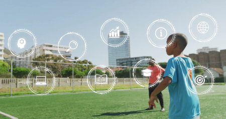 Running boy in blue jersey with coach following across soccer field with digital icons, copy space....