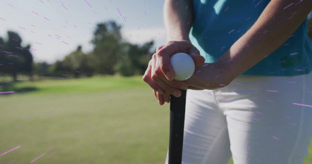 Golfer wearing teal polo gripping golf club, placing golf ball on golf course fairway, copy space....