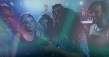 Smiling group of friends taking selfie at music venue, with smartphone and stage lights. Concert,...