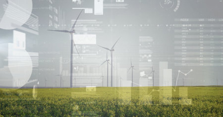 Monitoring central wind turbines generating power over yellow crop field with digital data overlays....