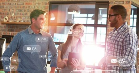 Standing professionals around office desk discussing data with tablet and notification icons....
