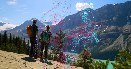 Standing hikers facing turquoise lake on trail with roots and orange and teal backpacks, copy space....