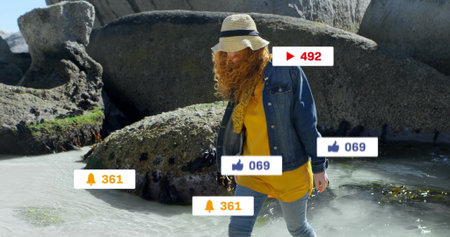 Walking woman wearing straw sun hat and denim jacket at beach cove. Coastal, leisure, outdoor,...