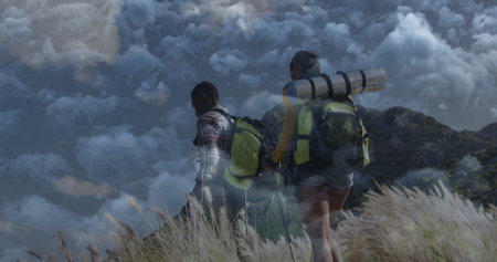 Climbing hikers ascending grassy mountain slope, with backpacks trekking poles sleeping pads....
