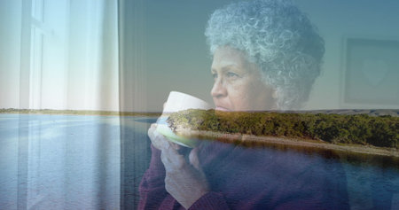 Woman in purple sweater holding ceramic mug by window at home, with lake reflection, copy space....