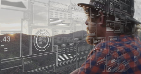 Standing man wearing safety helmet, plaid shirt analyzing AR data panels on hillside, copy space....
