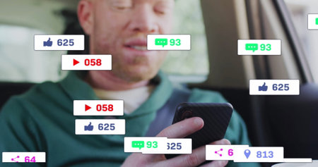 Man wearing hoodie scanning smartphone inside car front seat, with floating social media icons....