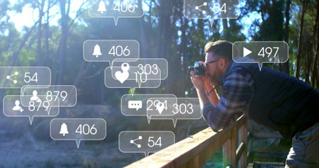 Leaning photographer shooting forest from wooden railing with DSLR and notifications, copy space....