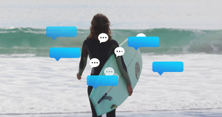 Standing woman surfer holding light-blue surfboard at shoreline, with wetsuit. Adventure, outdoor,...