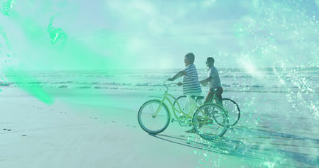 Pedaling mother and son along beach shoreline with yellow cruiser dark beach cruiser and footprints....