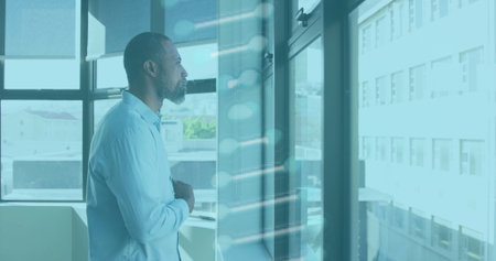 Standing man in light shirt gazing at glass window in office, with circuit graphic, copy space....