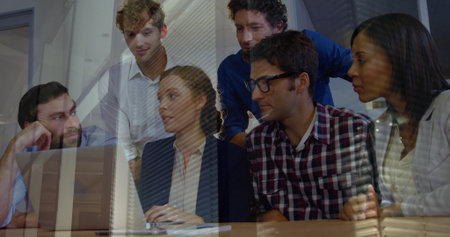 Collaborating business casual team studying laptop screen at conference table with notebook, pen....
