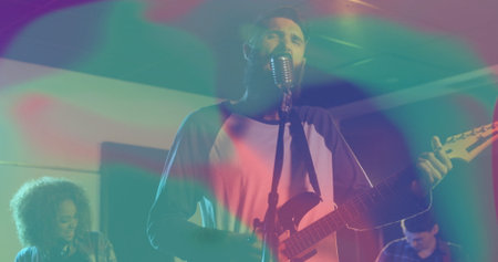 Performing bearded vocalist and guitarist strumming guitar singing on small stage, retro microphone....
