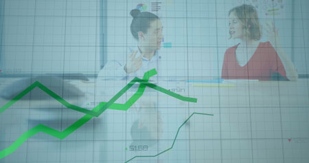 Discussing businesswomen analyzing line graphs on glass screen with laptop pen at conference table. Corporate, teamwork, innovation, analytics, presentation, professionalism, growthの写真素材