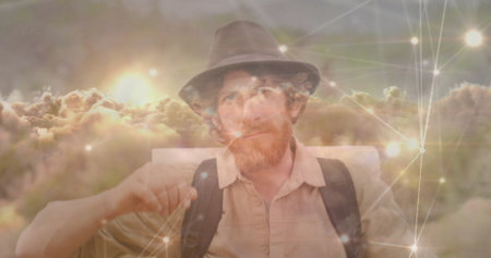 Man in fedora, button-up shirt with backpack gazing at sunset clouds, with network nodes and lines. Futuristic, digital, technology, outdoor, conceptual, innovation, connectivityの写真素材
