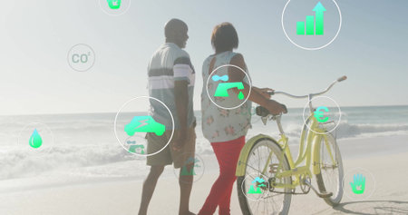 Strolling mature couple pushing yellow bicycle along sandy shoreline. Adventure, leisure,...
