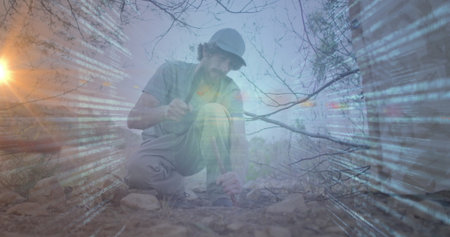 Chiseling male researcher kneeling with hammer tool and rock sample on arid terrain, code overlay....