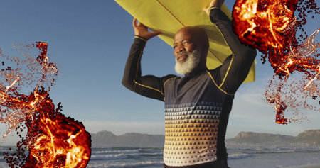 Holding mature surfer lifting yellow surfboard at beach, with patterned top, neoprene pants. Beach,...