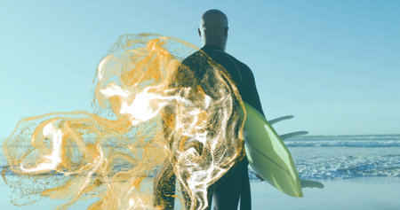 Standing surfer in black wetsuit holding yellow surfboard at ocean shore, with golden digital swirl....