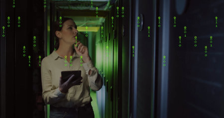 Analyzing IT engineer in jeans holding tablet in server corridor, with racks cables binary overlay....
