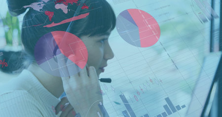 Monitoring call center agent analyzing financial charts on monitor in office, with headset mic....