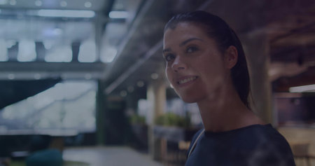 Standing businesswoman in office, with glass walls, overhead lights and lounge chairs, copy space. Professional, corporate, modern, sleek, workplace, collaboration, minimalistの写真素材