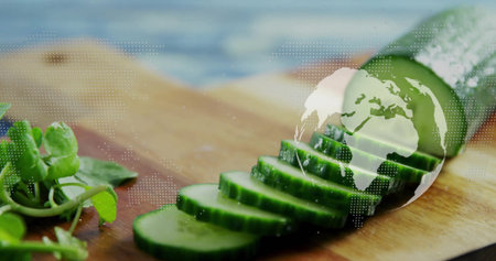 Displaying halved cucumber with sliced rounds on kitchen prep board, floating globe map with greens. Freshness, culinary, organic, health, minimalist, natural, technologyの写真素材