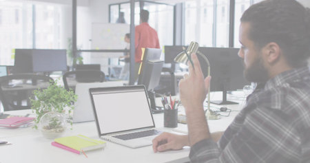Adjusting lamp, male in plaid shirt sitting at office desk with open laptop, terrarium, copy space. Collaboration, teamwork, modern, productivity, innovation, workspace, professionalの写真素材