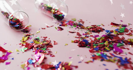 Colorful confetti scattered from glass over star image on pink background. Celebration, party, festive, vibrant, cheerful, funの写真素材