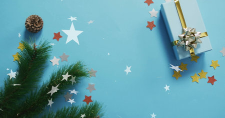 Christmas decorations with gift box over star confetti image on blue background. holiday, festive, celebration, present, winter, seasonalの写真素材