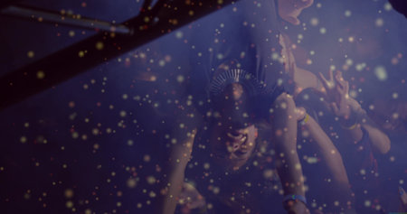 Lifting crowd-surfer upside down at concert under metal truss lights, with golden confetti drifting. Festival, atmosphere, energy, camaraderie, celebration, vibrant, dynamicの写真素材