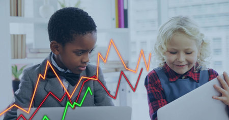 Boy in suit and girl in pinafore analyzing data at desk, with laptops and line-graph overlays. Collaboration, education, data, technology, teamwork, productivity, youthの写真素材
